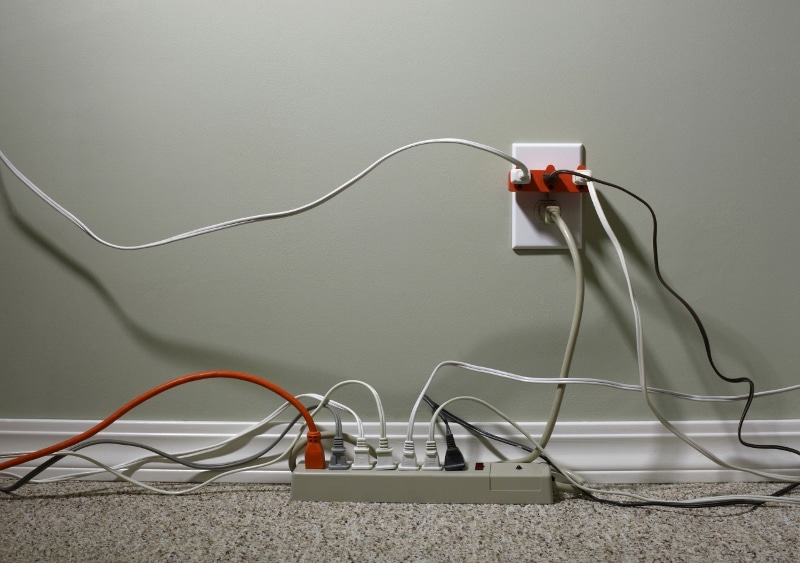 Still Life of an Electrical Wall Outlet Overloaded with Plugs and Extension Cords
