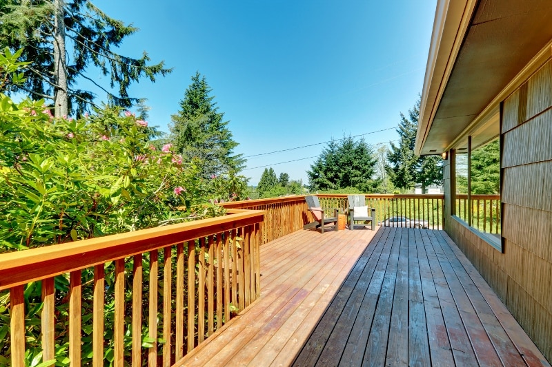 Long Deck, terrace with wood railings and green landscape.